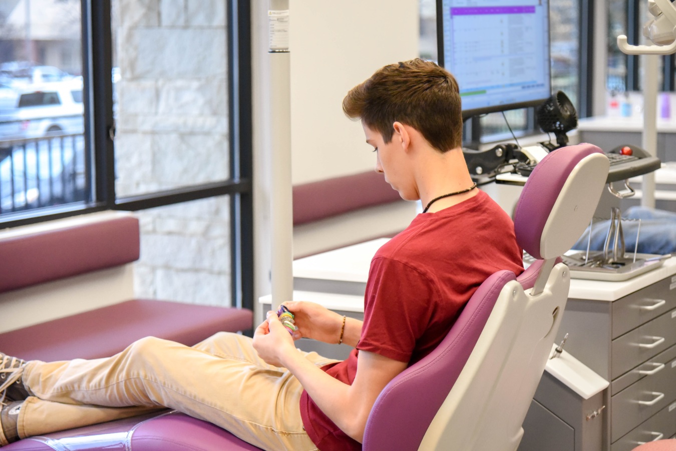 Teen patient holding colorful braces accessories at Purple Orthodontics in Auburn CA