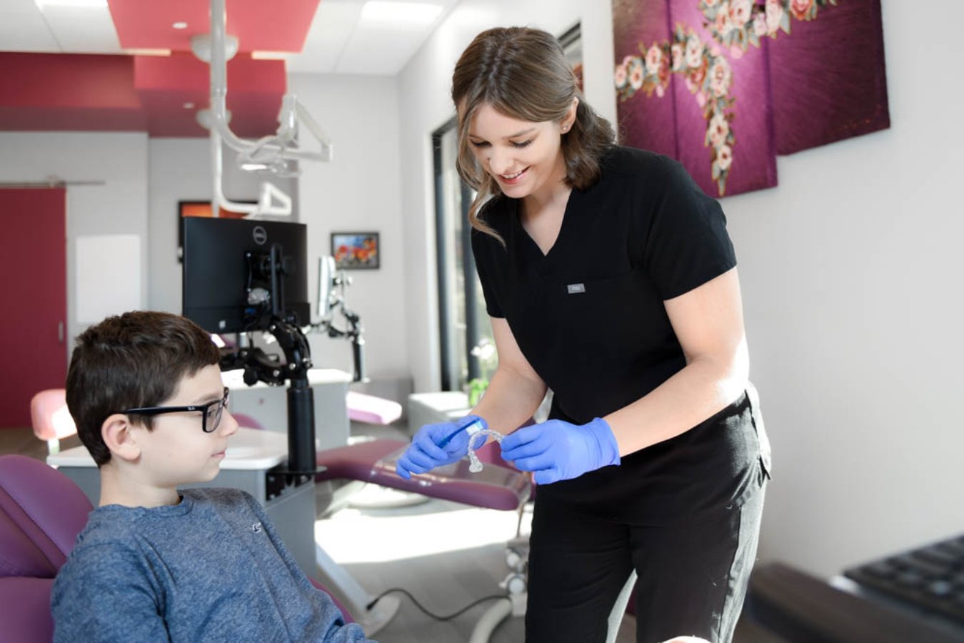 Teen patient holding Invisalign clear aligners during a first orthodontist visit